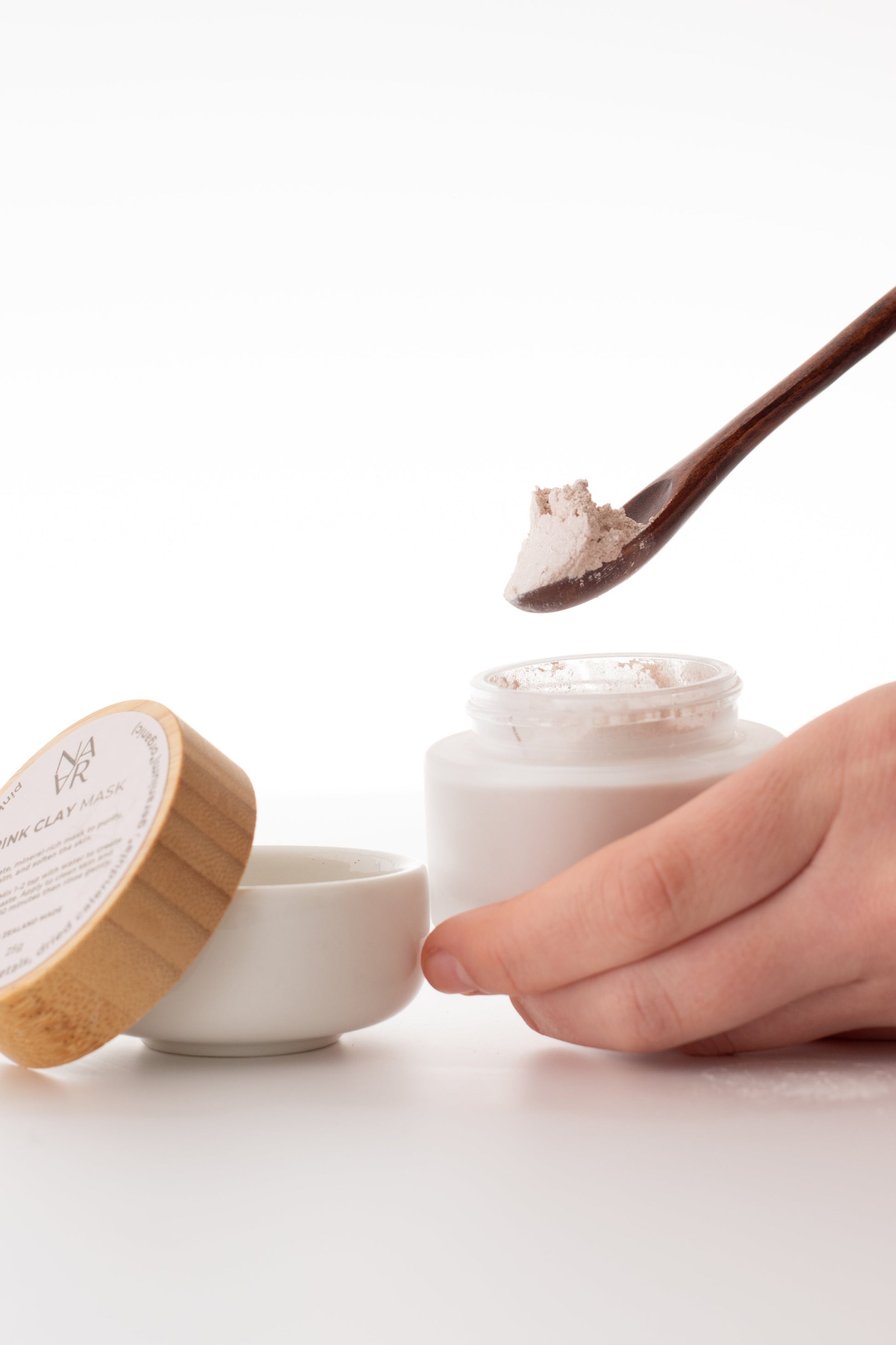 Natural Pink clay mask in eco-friendly container with wooden lid on a white background. Wellness for women / NARA