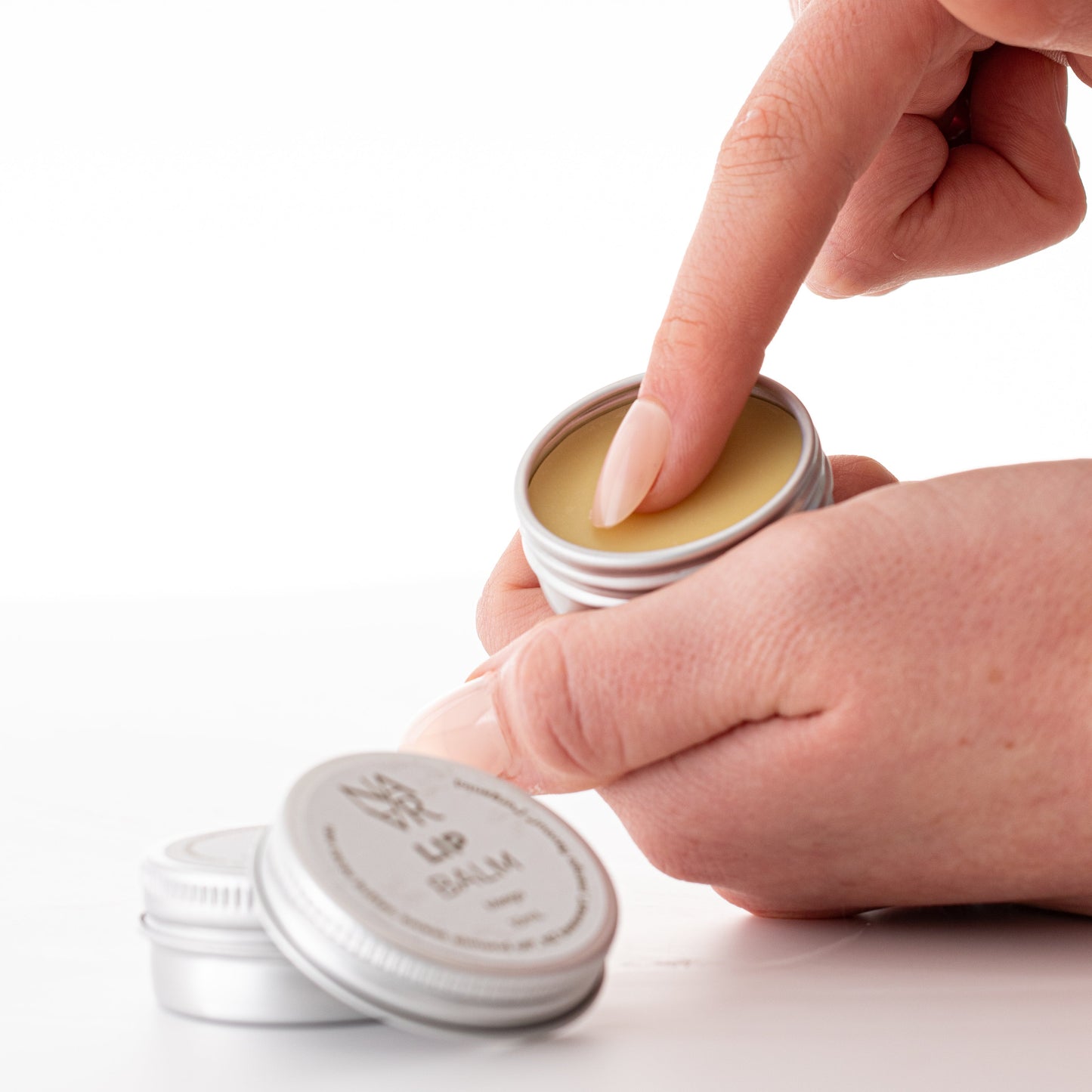 Hand with Vanilla organic Lip Balm made with natural ingredients on a white background